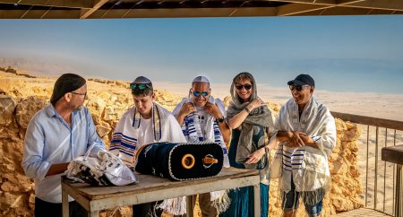 בר מצווה קורא בתורה תחת פרגולה על רקע ים המלח